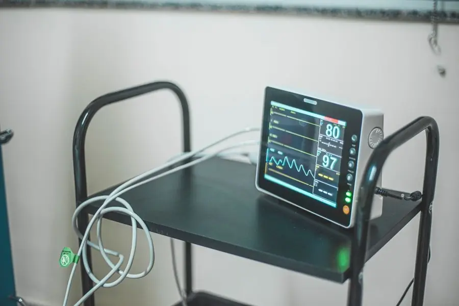 A patient monitoring screen on a mobile stand in a clinical room