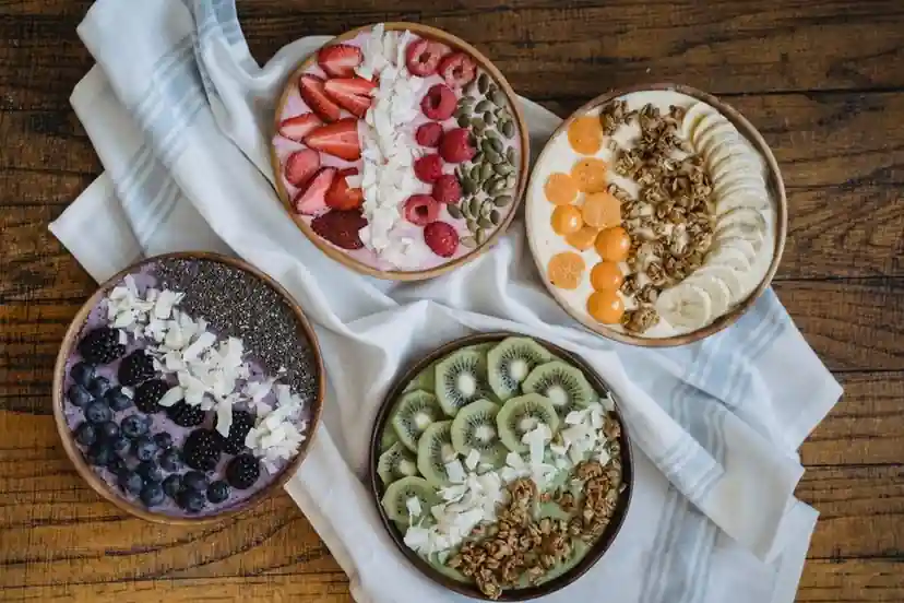 Colourful bowls of yogurt topped with berries, banana, kiwi and granola