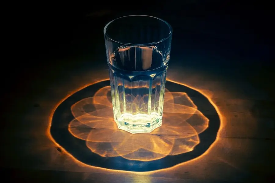 A glass of water lit from below on a wooden table